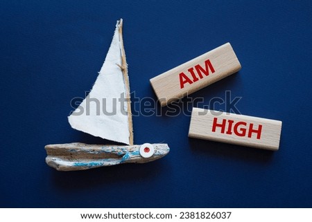 Aim High symbol. Wooden blocks with words Aim High. Beautiful orange background with boat. Business and Aim High concept. Copy space.