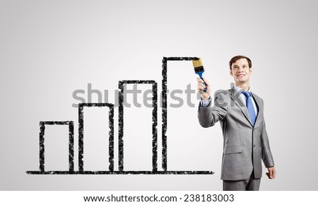 Young businessman painting graphs and diagrams with brush