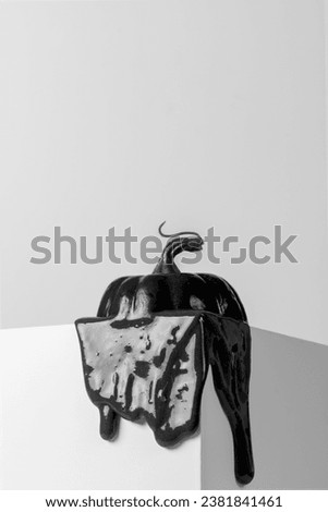 Creative Halloween concept. Black pumpkin melting on the edge of a white cube with copy space.   