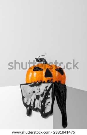 Creative Halloween concept. Halloween pumpkin melting on the edge of a white cube with copy space.   