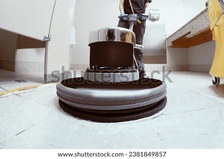 unrecognizable woman scrubbing the floor of a toilet with a machine Royalty-Free Stock Photo #2381849857