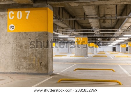 A spacious underground parking lot with clear markings, signs and designated parking zones, showcasing a well-organized and neat design. Royalty-Free Stock Photo #2381852969