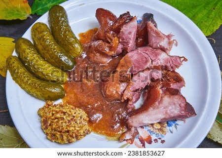 Close up picture of deboned smoked pork knuckle slowly roasted in dark beer served with pickles and rustic style mustard. Seasonal and traditional dish of central european cuisine served in autumn.