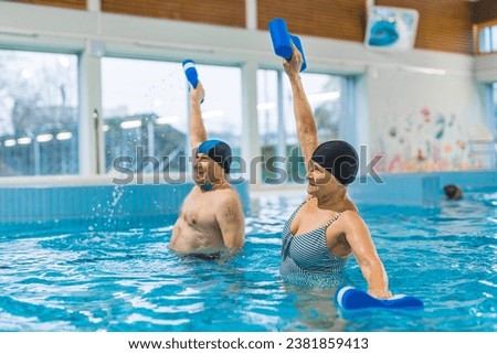 Grandparents taking care of their health. Senior adult caucasian married couple doing aqua fitness exercises with pool buoys. High quality photo Royalty-Free Stock Photo #2381859413