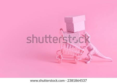 Pink Friday concept. Funny pink dinosaur toy with shopping cart full of present boxes on pink background