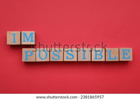 Motivation concept. Changing word from Impossible into Possible by removing wooden cubes on red background, flat lay