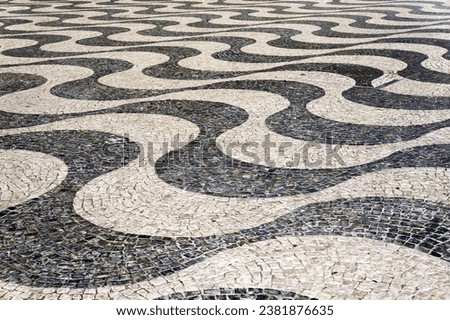 Traditional Mosaic Tiles Pavement Wavy Pattern on Streets and Squares in Lisbon, Portugal.                        Royalty-Free Stock Photo #2381876635