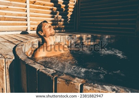 Man relaxing in wooden hot tub outdoor. . High quality photo