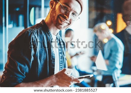 Portrait of cheerful hipster guy dressed in casual wear smiling at camera