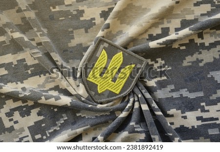 Symbol of Ukrainian army on the camouflage uniform of a Ukrainian soldier. The concept of war in Ukraine, patriotism and protecting your country from russian occupiers