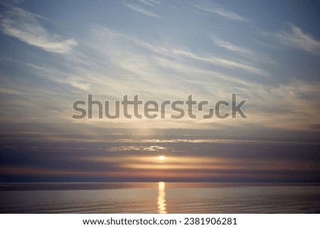 Amazing scenery with sky coloured by the sunset reflecting the calm sea water, selective focus. High quality photo