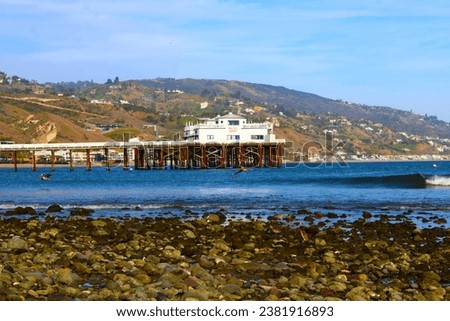 a gorgeous summer landscape at Malibu Pier at sunset with ocean water and homes along the mountains with lush green trees in at Malibu Lagoon in Malibu California USA Royalty-Free Stock Photo #2381916893