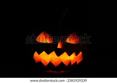Carved halloween pumpkin jack-o-lantern glows in darkness