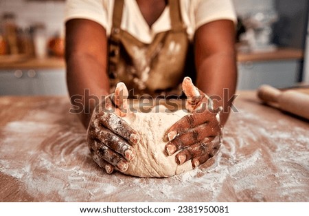 Details in baking process. Close up of black female hands molding raw dough on wooden table powdered with flour. Experienced housewife working accurate with bread base to fill with air for softness. Royalty-Free Stock Photo #2381950081