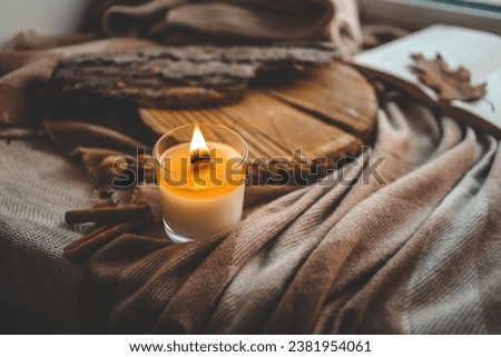 Burning candle in home interior, autumn aesthetics.