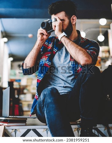 Bearded young man working photographer in studio and making photos on vintage camera
