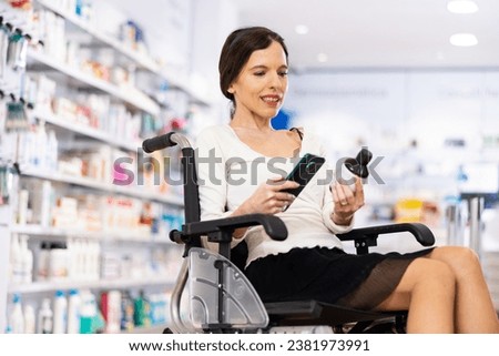Disabled woman in wheel-chair photographing medicine with smartphone in drugstore.