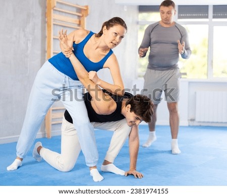 Guy and woman in sparring practice technique practicing basic attacking movements and maneuvers. Class self-defense training in presence of experienced instructor Royalty-Free Stock Photo #2381974155