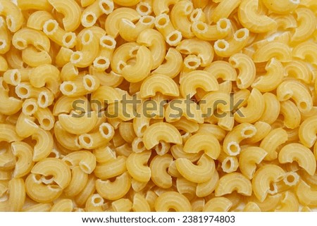 Background from uncooked macaroni pipe rigate (pipa rigata). Raw pasta background Royalty-Free Stock Photo #2381974803