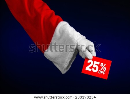 Christmas and New Year discounts topic: Hand of Santa Claus holding a red card with 25 % discount on an isolated dark blue background