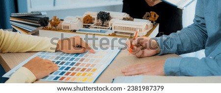 Cropped image of professional interior design team discuss about color and material usage for the project while project manager choose main theme color with house model on meeting table. Variegated. Royalty-Free Stock Photo #2381987379