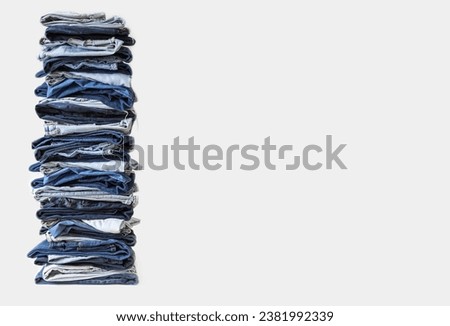Stack of various shades of blue jeans on white background. Lots of jeans pants in a stack. The concept of buying, selling, shopping and trendy modern clothes. Royalty-Free Stock Photo #2381992339