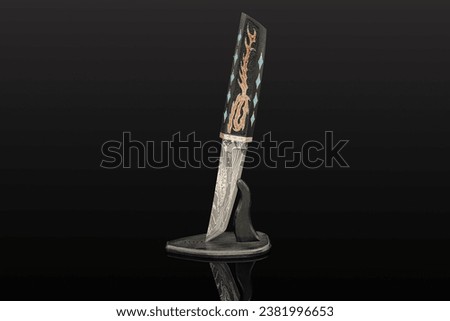 hand-forged Japanese samurai knife tanto with inlays in the form of hieroglyphs in black dener on a black background Royalty-Free Stock Photo #2381996653