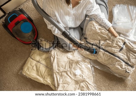 Woman compressed vacuum technology clothes easy compressing comfortable storage organizing top view. Female tidying up general cleaning garment enclosed bag keeping method household and housekeeping Royalty-Free Stock Photo #2381998661
