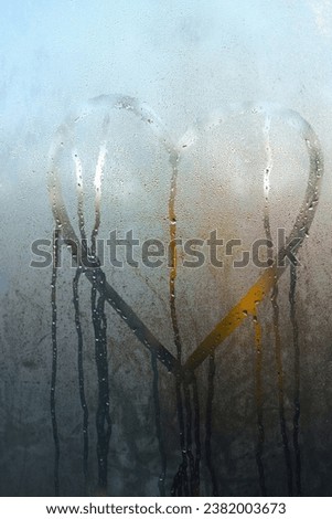 Heart shaped drawing on the window in the morning on wet glass