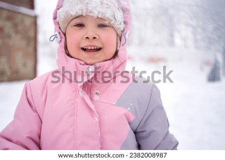 A girl in winter clothes stands on the street.