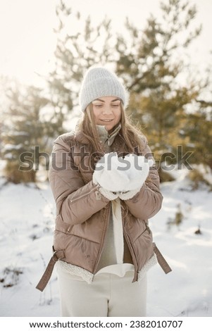 Portrait of a young woman standing in forest at winter day