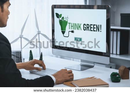 Businessman working in office developing plan or project on eco-friendly alternative energy with solar cell technology display on computer screen for greener environment as apart of CSR effort. Gyre