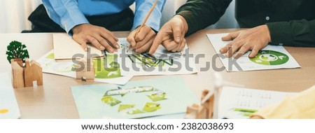 A cropped picture of green city poster was placed at green business meeting on meeting table with environmental document, wooden house block and windmill model scattered around. Closeup. Delineation.