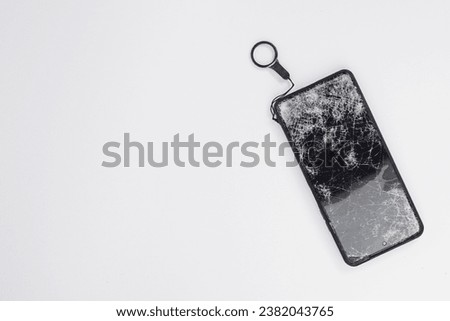 Mobile smartphone with broken screen isolated on white background with keychain