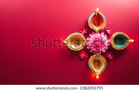 Happy Diwali - Clay Diya lamps lit during Diwali, Hindu festival of lights celebration. Colorful traditional oil lamp diya on red background Royalty-Free Stock Photo #2382050795