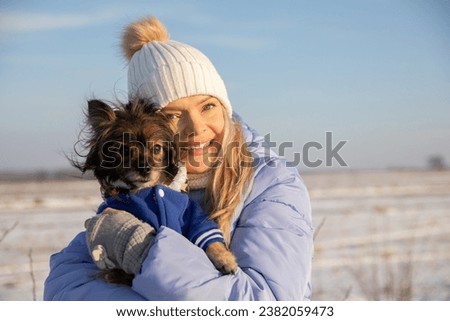 The girl poses for a photo with her dog, which she holds in her arms.