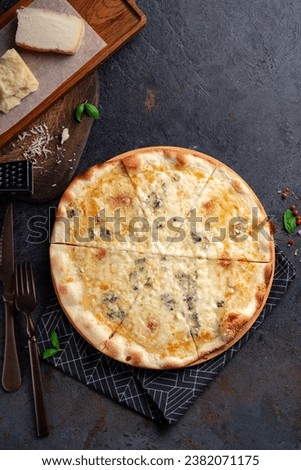 Pizza four cheeses on a dark background. Pizza 4 cheeses with gorgonzola, cheddar, mozzarella and parmesan. Top view Royalty-Free Stock Photo #2382071175