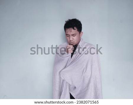 Adult Asian man having sore throat and coughing while using blanket Royalty-Free Stock Photo #2382071565