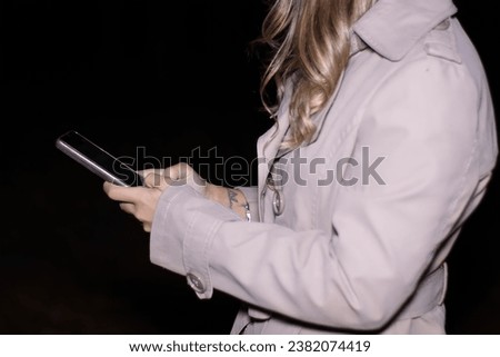 close-up of an unrecognizable woman using her cell phone at night, horizontal dark night background