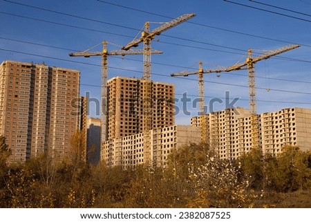 Unworthy multi-storey buildings. Construction cranes and blue sky Royalty-Free Stock Photo #2382087525