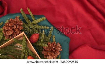 Fir leaves, dried pine, and gift box spinning on red background. Concept of Christmas and New Year presents, festive and holiday shopping