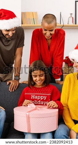 Young family opening christmas presents at home together. Adorable teen girl unpacking gift on sofa for xmas eve.