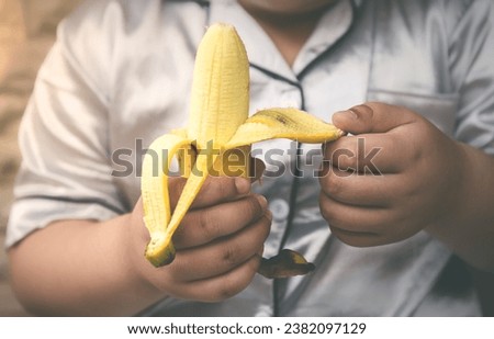 Ripe bananas in child 's hand with natural light and dark gray tones