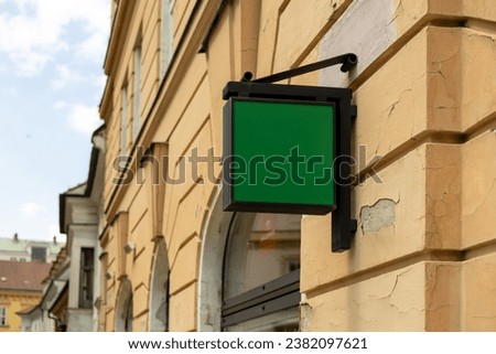 Blank sign mockup in the urban environment. Green rectangle sign with blank space for cafe or restaurant name and logo, in an old town