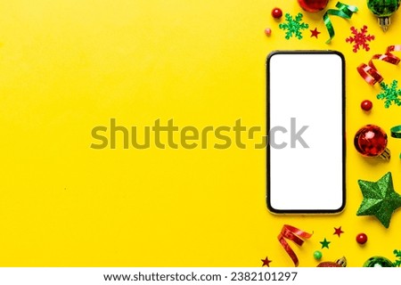 Christmas online shopping from home phone with blank white display top view. smart mobile with copy space on colored background with Christmas decorations balls,. Winter holidays sales background.