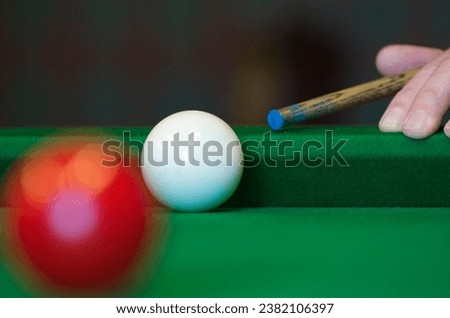 A close up of the white cue ball on a snooker table during play and a hand with the snooker cue stick about to take a shot Royalty-Free Stock Photo #2382106397