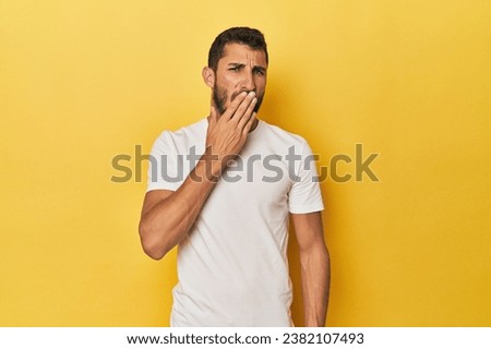 Young Hispanic man on yellow background yawning showing a tired gesture covering mouth with hand. Royalty-Free Stock Photo #2382107493