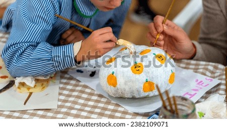 Children's drawing class. Boy painting a pumpkin with his mom
