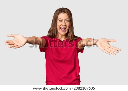 Middle-aged woman portrait in studio setting feels confident giving a hug to the camera.