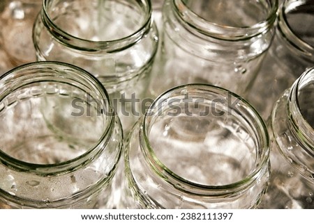 several washed transparent glass jars stand upside down, top view, prepared for pickling, salting, preparations for the winter Royalty-Free Stock Photo #2382111397